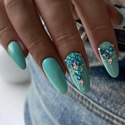 Unhas em verniz azul turquesa com decoração de pedraria azul e branca