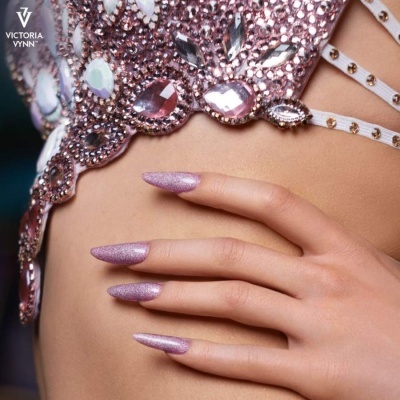 Top rosa com pedras brilhantes e mão com unhas rosas compridas