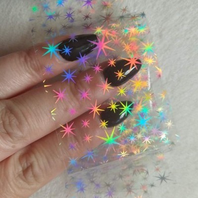 Mãos com unhas pretas seguram filme de estrelas holográficas