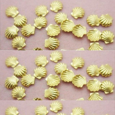 Contas douradas em forma de conchas sobre fundo rosa