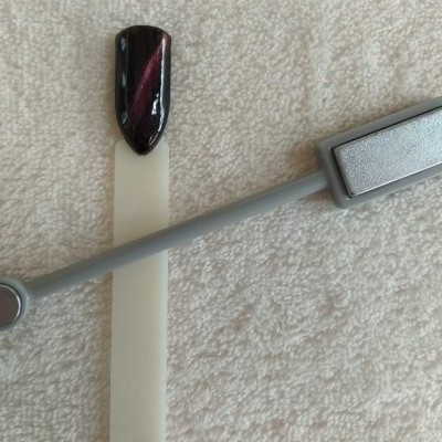 Acessório magnético cinzento e palete de teste com verniz preto e vermelho sobre toalha branca