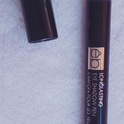 Lápis sombra de olhos lilás com tampa preta sobre superfície branca