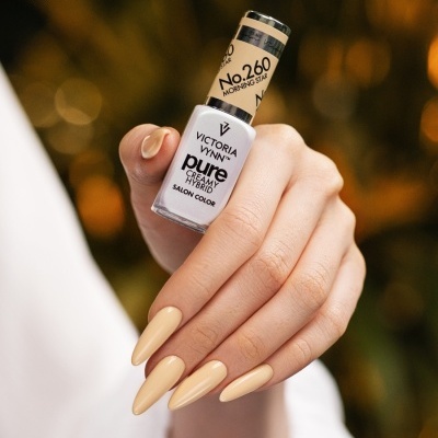 Frasco de verniz de unhas Victoria Vynn em mão com unhas pintadas de cor bege clara