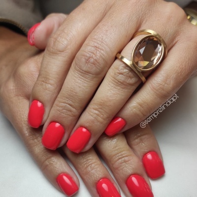 Mãos femininas com unhas vermelhas e anel dourado com pedra oval