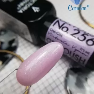 Esmalte de unhas rosa perolado com embalagem preta e texto visível num fundo quadriculado branco.