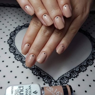 Unhas pintadas de nude rosa com pontos pretos e frascos de verniz Victoria Vynn