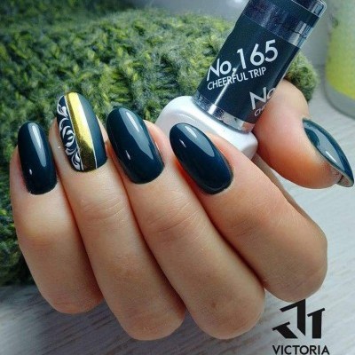 Unhas pintadas em preto e dourado com padrão floral branco e frasco de verniz gel preto