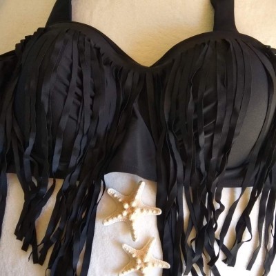Top de bikini preto com franjas longas num fundo com toalha branca e estrelas-do-mar