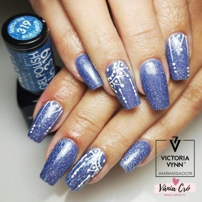 Unhas gel polish azul brilhante com desenhos brancos abstratos e frasco de esmalte ao fundo