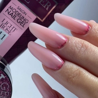 Unhas compridas pintadas de gel rosa claro e embalagem do produto Master Gel.