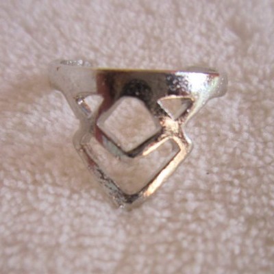 Anel prateado com design geométrico sobre tecido branco