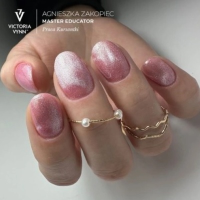 Unhas rosa metálicas com anéis dourados finos e pérolas.