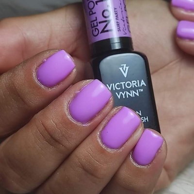 Mãos com unhas pintadas de verniz gel lilás segurando frasco de verniz Victoria Vynn