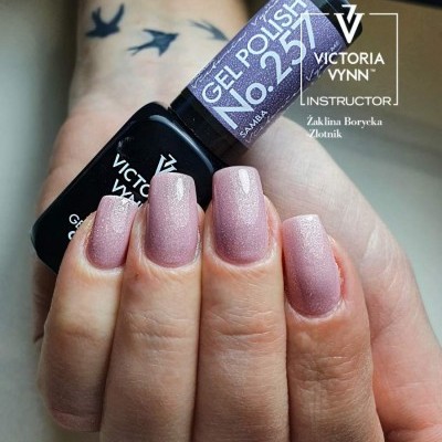 Unhas femininas pintadas de rosa cintilante segurando verniz gel Victoria Vynn