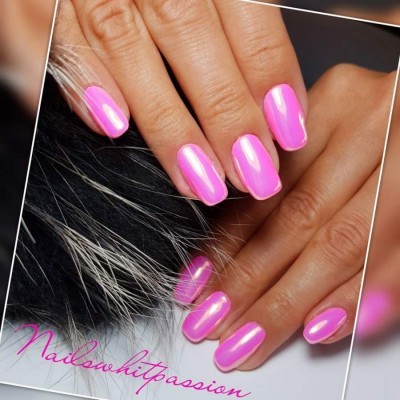 Mãos com unhas pintadas de rosa neón brilhante sobre pêlo preto e branco.