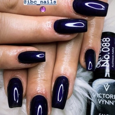 Unhas com verniz gel roxo escuro brilhante e frasco de verniz Victoria Vynn próximo