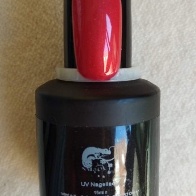 frasco de verniz UV preto com amostra de cor vermelha