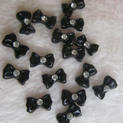 Pequenos laços pretos com brilhante no centro sobre tecido branco felpudo