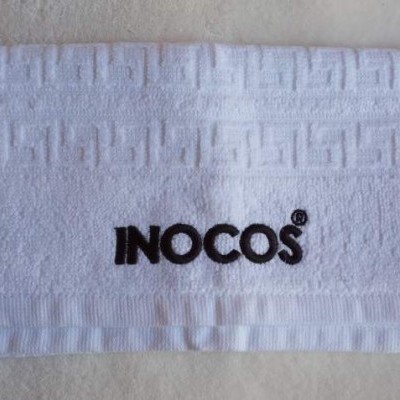 Toalha branca com padrão geométrico e bordado INOCOS®