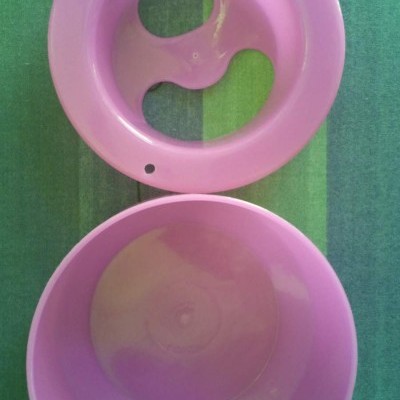 Duas peças plásticas cor-de-rosa, uma com furos, outra lisa