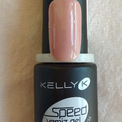 Frasco de verniz gel KELLY K preto com amostra de cor rosa claro na unha