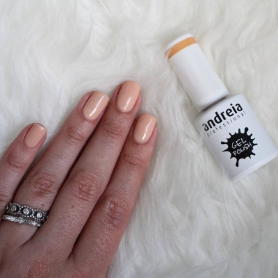 Unhas pintadas cor nude e frasco de verniz gel Andreia Professional sobre fundo branco