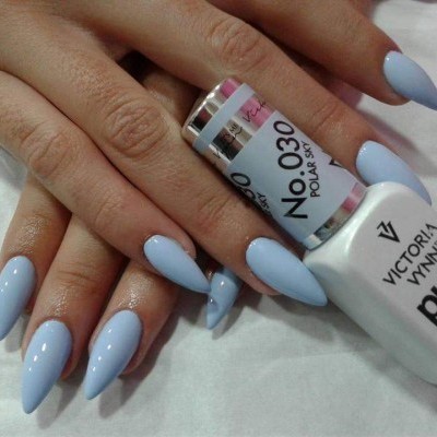 Mãos com unhas azuis claras e frasco de verniz