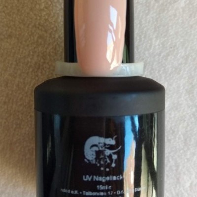 frasco preto de verniz de unhas UV com amostra de unha nude creme