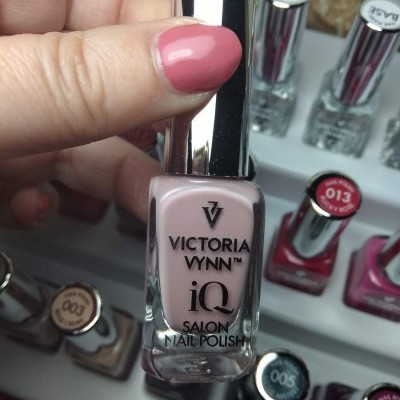 Frasco de verniz de unhas rosa claro Victoria Vynn iQ com outros frascos atrás