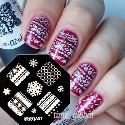 Unhas decoradas com padrões brancos sobre verniz vermelho vinho e carimbo preto com padrões de inverno