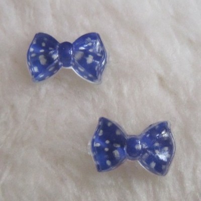 Brincos em forma de laço azul com pontos brancos sobre fundo branco peludo