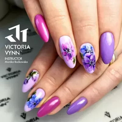 Unhas pintadas com verniz rosa e lilás com desenhos florais e texto Victoria Vynn no fundo