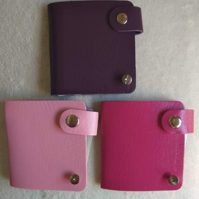 Três carteiras pequenas de couro sintético em rosa e roxo com botões metálicos