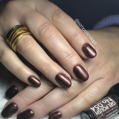 Unhas pintadas com verniz gel castanho metálico e anel dourado e preto