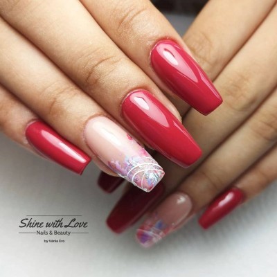 Unhas compridas vermelhas com uma unha decorada em tons pastel com detalhes prateados