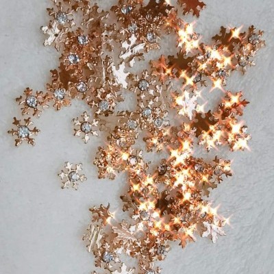 Enfeites dourados de flocos de neve com pedras brilhantes sobre fundo branco