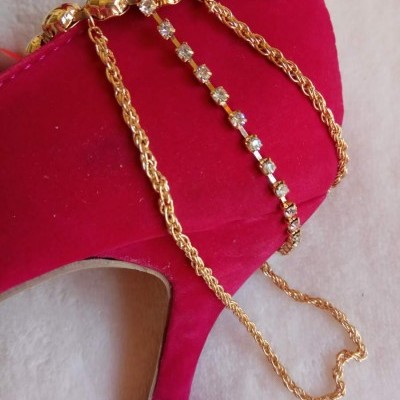 Sapato de salto alto vermelho em veludo com colares dourados e pedras brilhantes