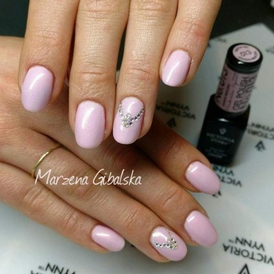 Unhas com verniz rosa claro e decoração de pedras pequenas