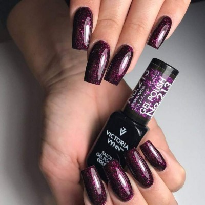 Unhas postiças com verniz gel roxo escuro brilhante segurando frasco de verniz