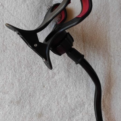 Suporte de telemóvel preto e vermelho com mola e braço flexível sobre tecido branco