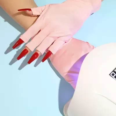 Mãos com luvas rosa e unhas vermelhas longas junto a dispositivo branco
