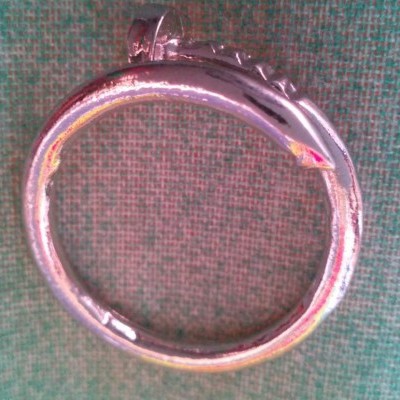 Anel prata em forma de cobra sobre tecido verde quadriculado