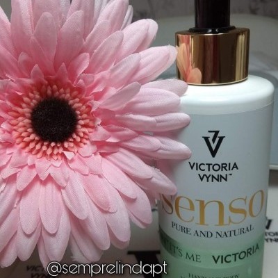 Frasco branco de creme para mãos e corpo Victoria Vynn com flor rosa artificial ao lado