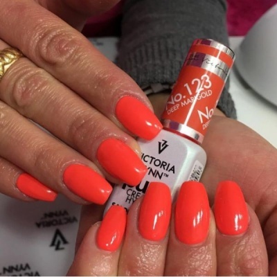 Unhas pintadas de verniz laranja vibrante seguram frasco Victoria Vynn No. 123 Deep Marigold