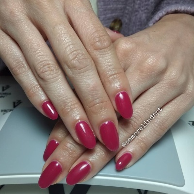 Mãos com unhas pintadas de vermelho escuro sobre superfície cinzenta