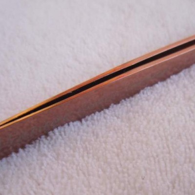 Pinça metálica cobre com ponta fina em superfície branca felpuda