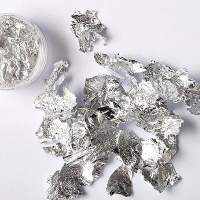Pedaços de papel de alumínio prateado amassados com recipiente pequeno