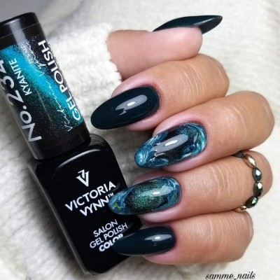 Esmalte de gel azul e verde em unhas compridas brilhantes com garrafa de esmalte e anel