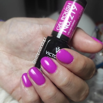Frasco de verniz gel roxo e unhas pintadas da mesma cor