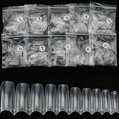 Unhas postiças transparentes organizadas por tamanho de 1 a 10 em sacos plásticos sobre fundo preto